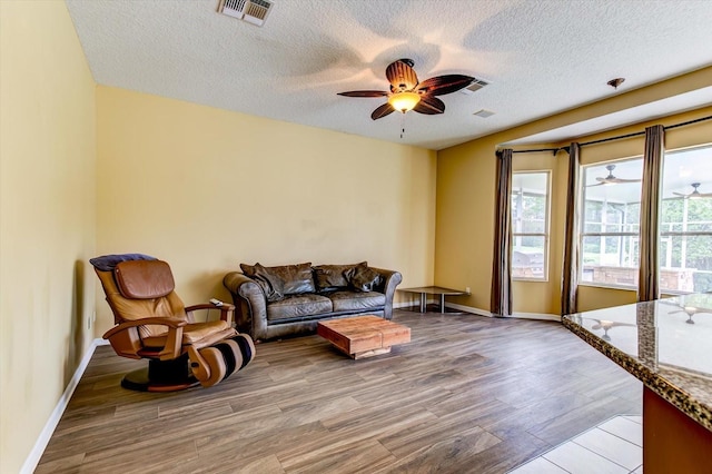 living room featuring a textured ceiling, ceiling fan, and light hardwood / wood-style flooring