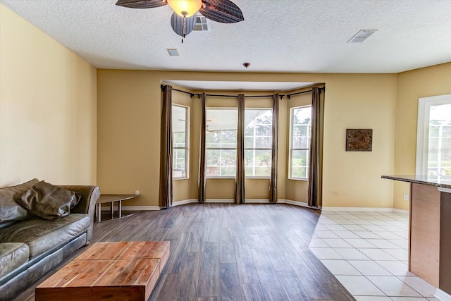 unfurnished living room with ceiling fan, a textured ceiling, and light wood-type flooring