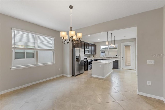 kitchen with a center island, pendant lighting, stainless steel appliances, light countertops, and a sink