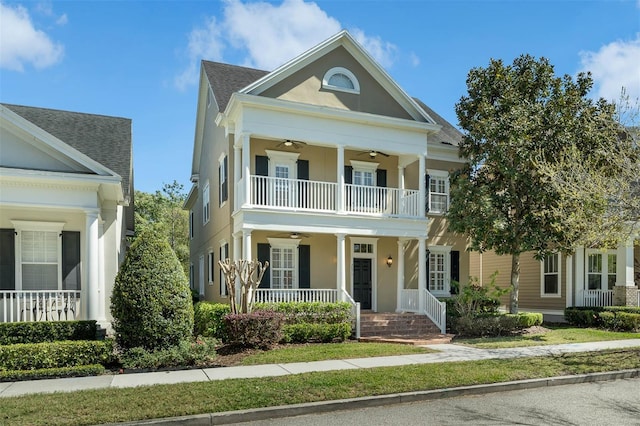 neoclassical / greek revival house featuring a ceiling fan, covered porch, a balcony, and stucco siding