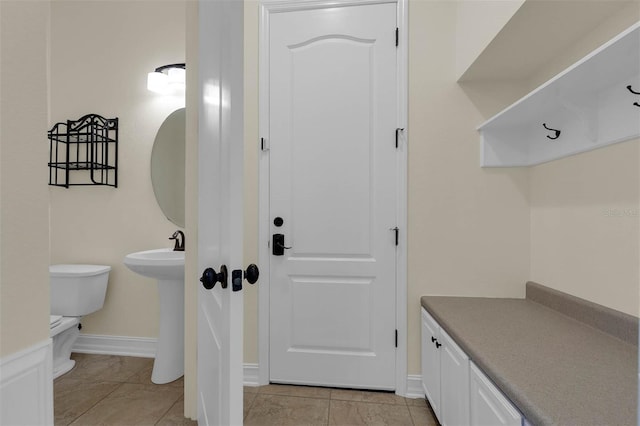 interior space with baseboards, a sink, and toilet