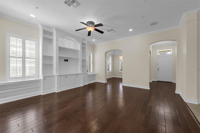 unfurnished living room featuring a textured ceiling, dark wood-type flooring, visible vents, baseboards, and ornamental molding