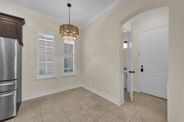 unfurnished dining area featuring arched walkways, light tile patterned floors, baseboards, and crown molding