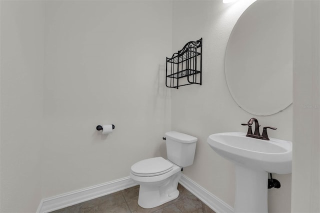 half bath with toilet, baseboards, and a sink