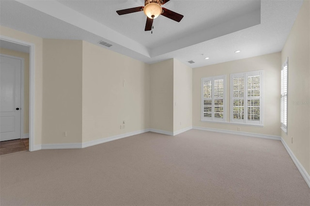 unfurnished room featuring visible vents, baseboards, light colored carpet, a tray ceiling, and recessed lighting