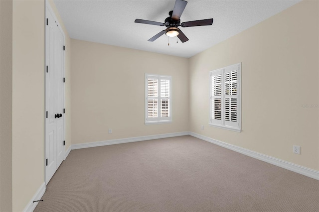 unfurnished room with a textured ceiling, ceiling fan, carpet flooring, and baseboards