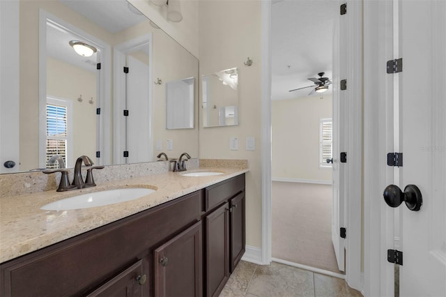 bathroom featuring double vanity, ceiling fan, baseboards, and a sink