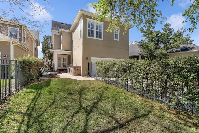 back of property with a garage, french doors, a fenced backyard, a yard, and stucco siding