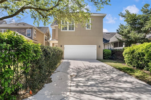 view of front facade featuring a garage, concrete driveway, and stucco siding