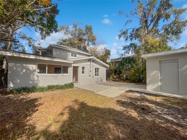 662 Lake Dr, Altamonte Springs, FL 32701 - back of house with an outbuilding, a patio, a lawn, and stucco siding