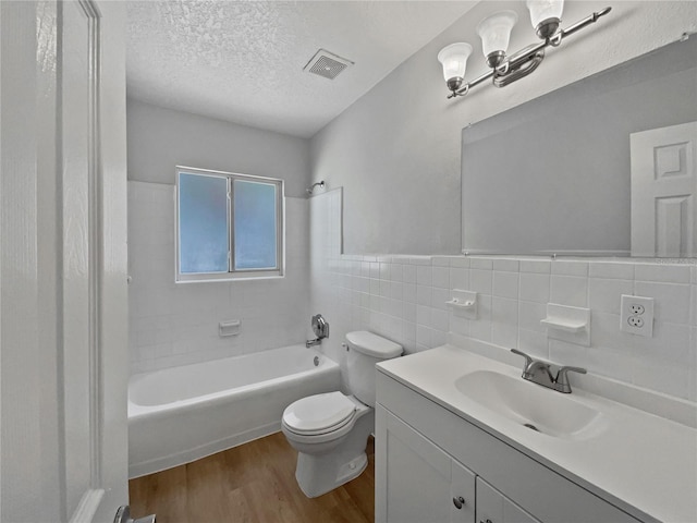 662 Lake Dr, Altamonte Springs, FL 32701 - bathroom with a textured ceiling, wood finished floors, vanity, visible vents, and tile walls