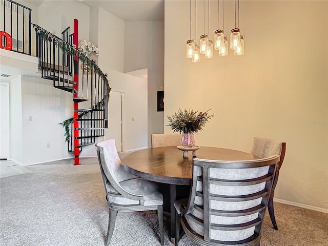 carpeted dining space featuring a high ceiling