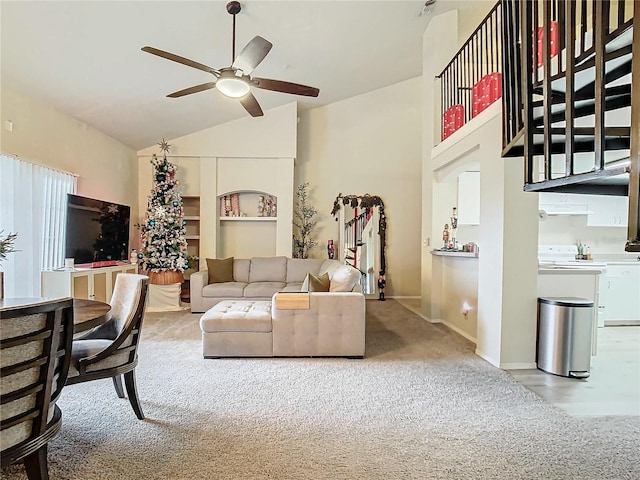 living room featuring ceiling fan, high vaulted ceiling, and light carpet