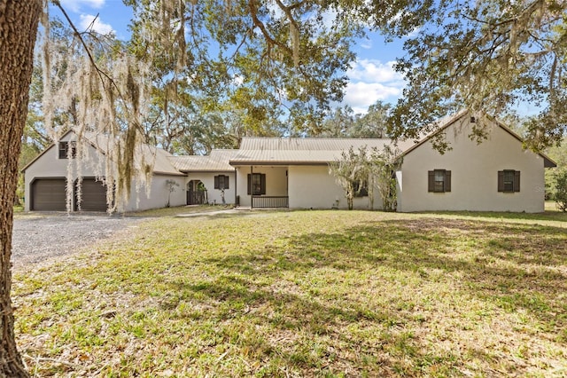 view of front of house with a garage, metal roof, a front lawn, and stucco siding