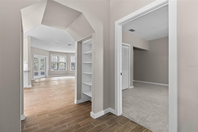 hall with wood finish floors, visible vents, and baseboards