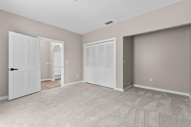 unfurnished bedroom featuring light colored carpet, a closet, visible vents, and baseboards