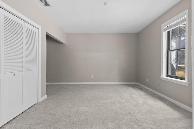 unfurnished bedroom featuring light carpet, baseboards, visible vents, and a closet