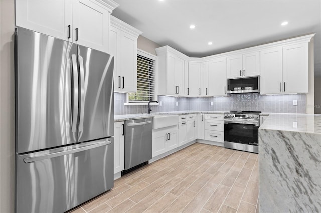 kitchen with white cabinetry, appliances with stainless steel finishes, tasteful backsplash, and light stone counters