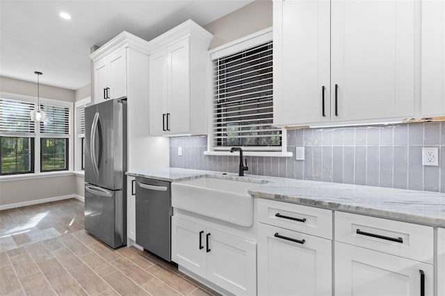 kitchen featuring white cabinets, light stone countertops, stainless steel appliances, and a sink