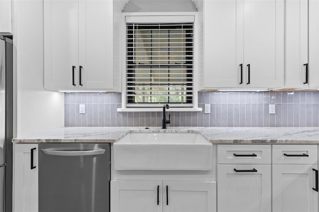 kitchen with light stone counters, stainless steel dishwasher, a sink, and white cabinetry