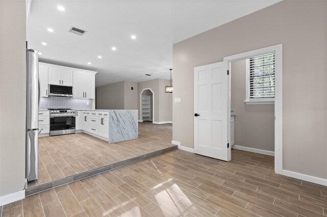 kitchen with visible vents, white cabinets, arched walkways, appliances with stainless steel finishes, and wood tiled floor