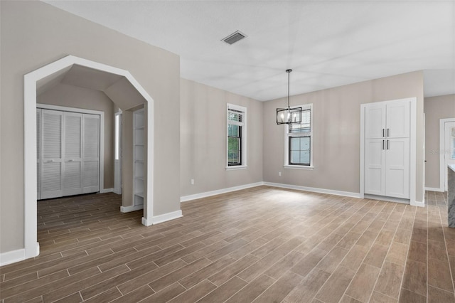 interior space featuring dark wood-style floors, baseboards, visible vents, and an inviting chandelier