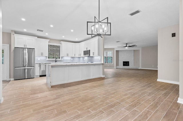 kitchen featuring pendant lighting, visible vents, freestanding refrigerator, open floor plan, and white cabinetry