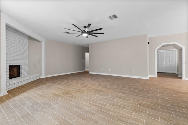 unfurnished living room with light wood finished floors, baseboards, visible vents, a ceiling fan, and a fireplace
