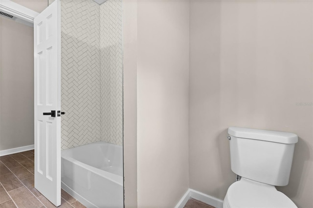 bathroom featuring toilet, visible vents, baseboards, and shower / washtub combination