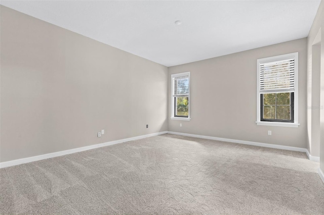 unfurnished room with baseboards and light colored carpet