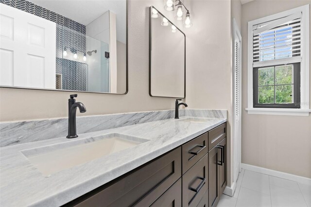 full bath with tile patterned flooring, a sink, baseboards, and double vanity