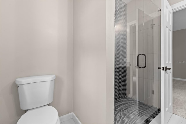 bathroom with toilet, a shower stall, and baseboards