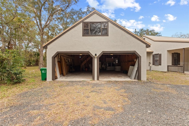 view of side of home featuring a garage, an outdoor structure, and stucco siding