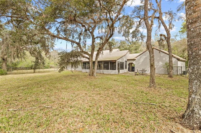 back of property featuring a yard, fence, and a sunroom