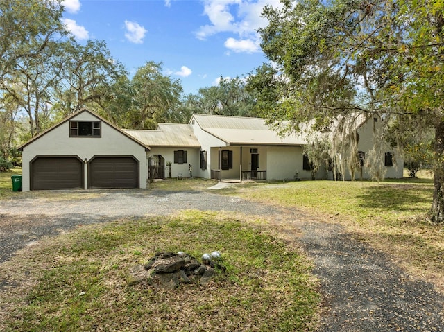 view of front of property with a garage, stucco siding, a front yard, and gravel driveway