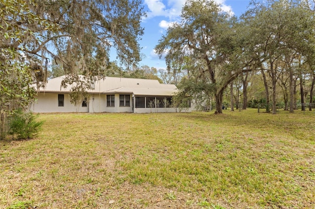 back of property featuring a sunroom, metal roof, and a lawn