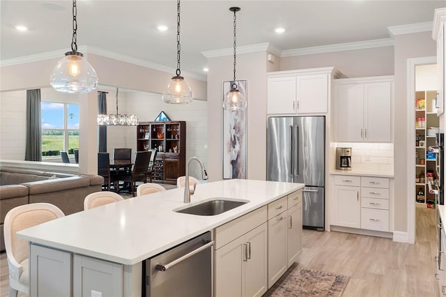 kitchen featuring stainless steel appliances, an island with sink, light countertops, and a sink