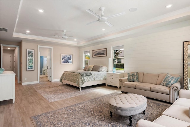 bedroom with ornamental molding, baseboards, light wood-style flooring, and a tray ceiling