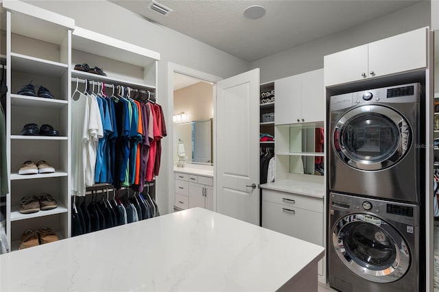 clothes washing area featuring stacked washer / dryer, cabinet space, and visible vents