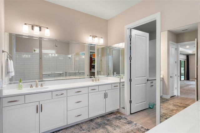 full bath featuring double vanity, a stall shower, wood finished floors, and a sink