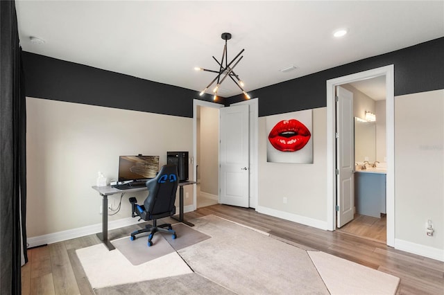 office area with baseboards, light wood-style floors, and a chandelier