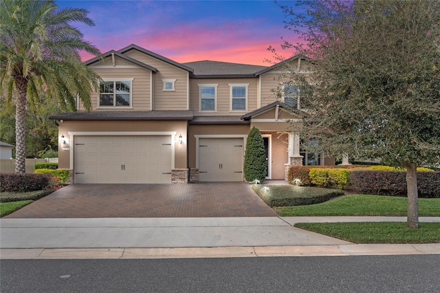 craftsman-style house featuring a garage, decorative driveway, and stucco siding