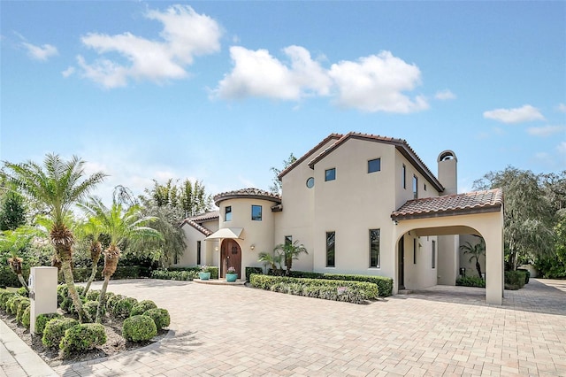 mediterranean / spanish home with decorative driveway, a tile roof, and stucco siding