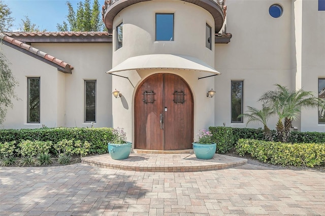 entrance to property with a tiled roof and stucco siding