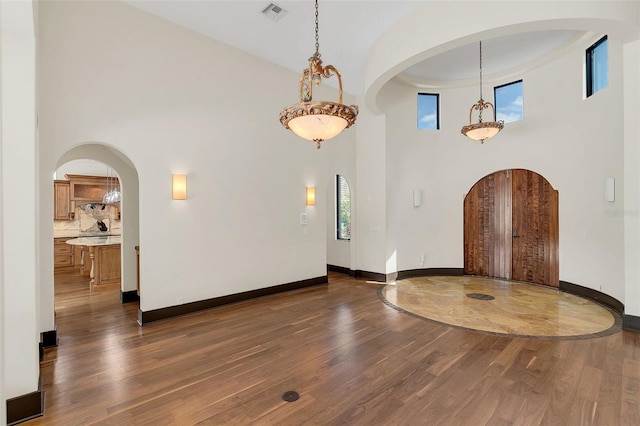 foyer featuring a healthy amount of sunlight, visible vents, arched walkways, and dark wood-style flooring