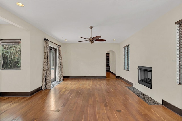 unfurnished living room with wood-type flooring, a fireplace with flush hearth, and baseboards