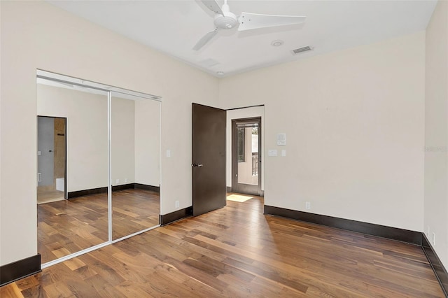 unfurnished bedroom with a closet, wood finished floors, visible vents, and baseboards