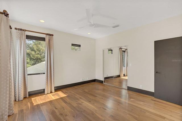 unfurnished room with a ceiling fan, wood finished floors, visible vents, and baseboards