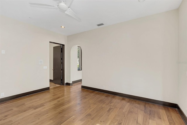 empty room with arched walkways, recessed lighting, visible vents, baseboards, and light wood-style floors