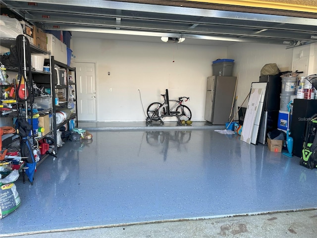 garage featuring a garage door opener and freestanding refrigerator